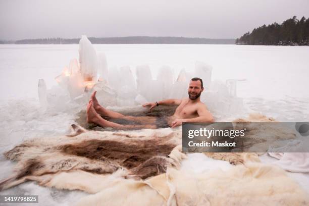 portrait of happy mature man enjoying ice bath at frozen lake - frozen man stockfoto's en -beelden