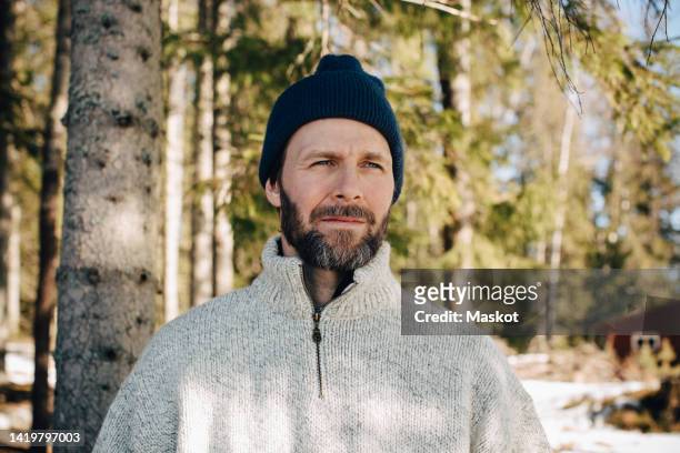 mature man wearing knit hat looking away in forest - contemplation outside stock pictures, royalty-free photos & images