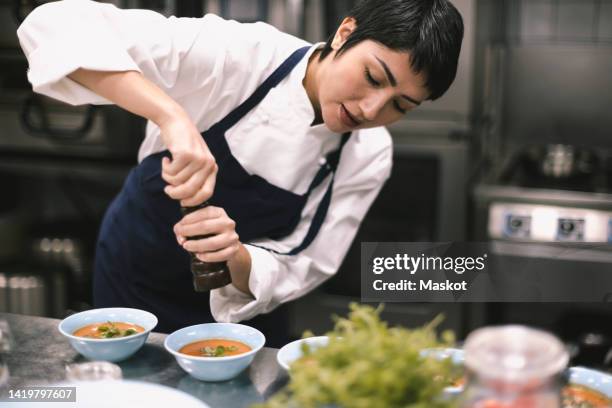 female chef adding pepper in soup at kitchen counter in restaurant - pepper mill bildbanksfoton och bilder