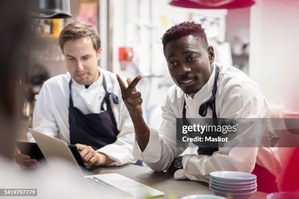 male chefs discussing at kitchen counter in restaurant - chef team stock pictures, royalty-free photos & images