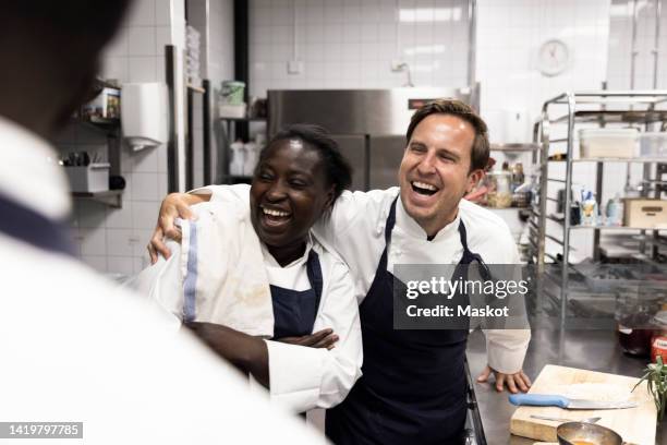 happy chef with arm around female colleague in commercial kitchen - chef happy stock pictures, royalty-free photos & images