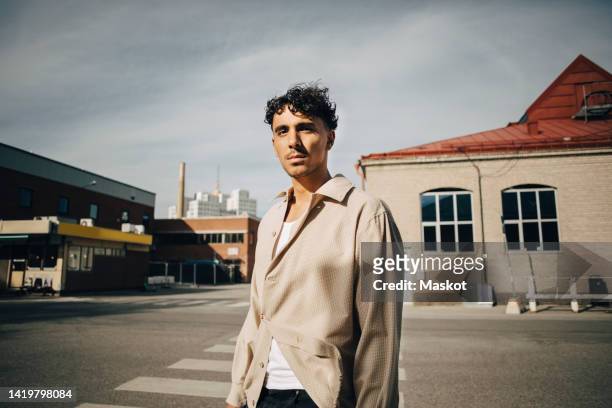 portrait of confident young man standing on street - blank expression imagens e fotografias de stock