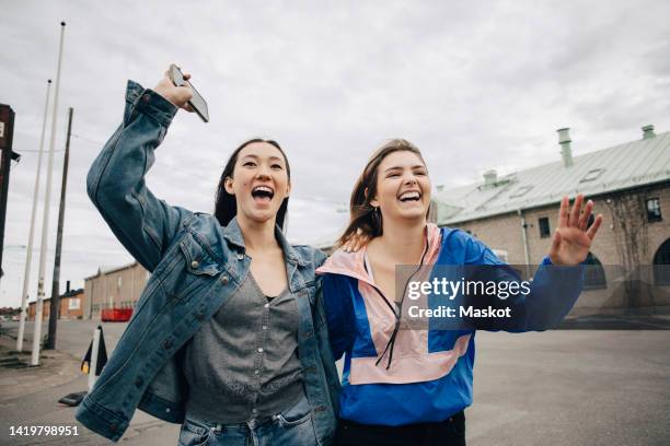 carefree multiracial young women walking on street in city - female waving on street stock pictures, royalty-free photos & images