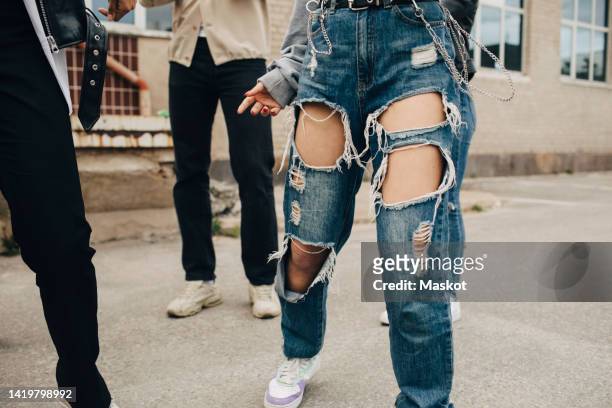low section of woman wearing torn jeans dancing with friends on street - lap dancing stockfoto's en -beelden