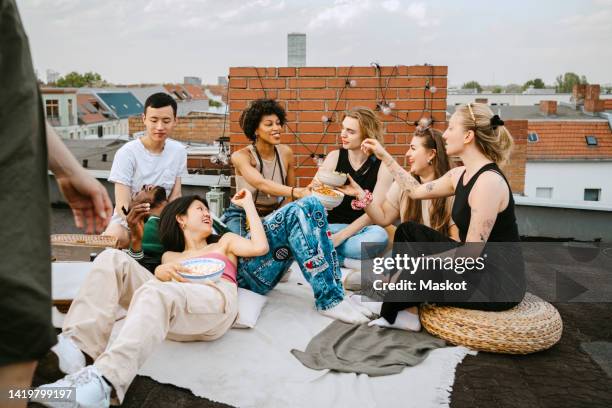 happy multiracial friends enjoying party on rooftop - snacks stock-fotos und bilder