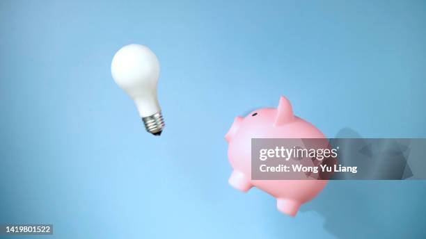 pink piggy bank jumping while chasing light bulb - saving electricity stock pictures, royalty-free photos & images