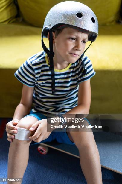 small boy after an accident with his skateboard. he is sitting at home and suffering - kid skateboard stock pictures, royalty-free photos & images