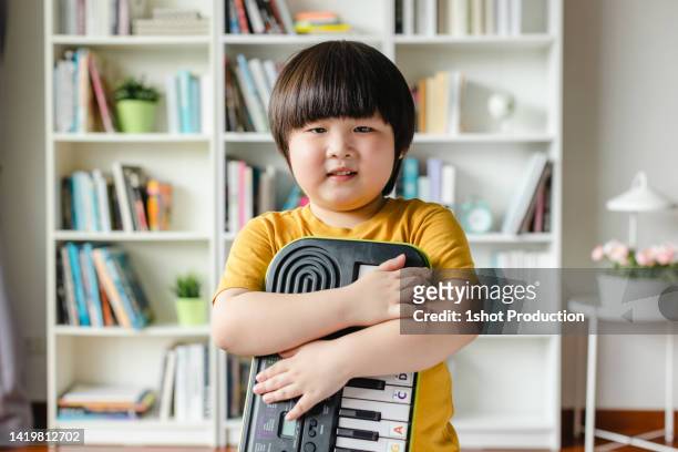 niño activo sosteniendo el teclado, vertical. - toma mediana fotografías e imágenes de stock