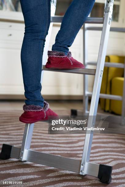 woman climbing on a ladder at home - red house slippers stock pictures, royalty-free photos & images