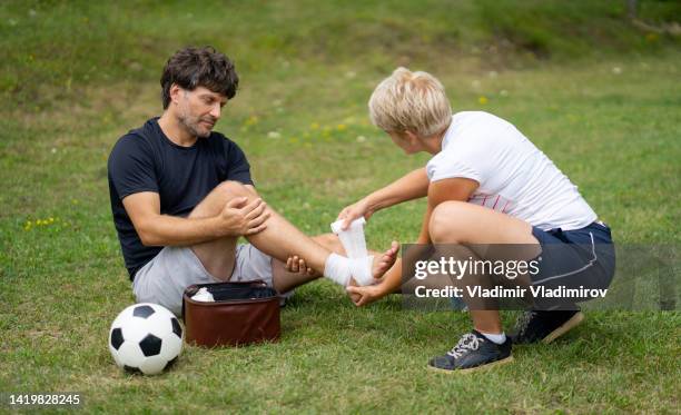 ein mann erhält erste-hilfe-hilfe, nachdem er beim fußballspielen draußen erste-hilfe-hilfe hatte - erste hilfe stock-fotos und bilder