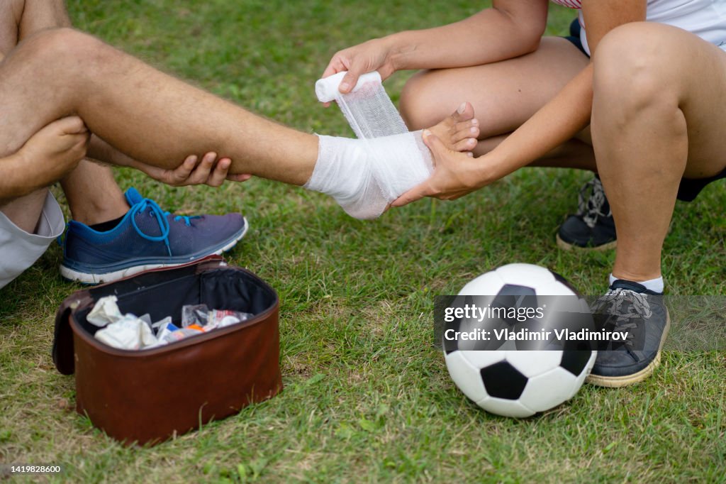 A man is receiving first aid help after having an accident while playing football outside