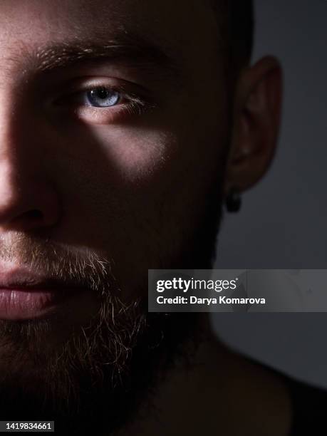 half face of brutal man with beard, moustache, blue eyes on grey isolated background. close up portrait of serious middle aged man with earring. - belleza y estetica fotografías e imágenes de stock