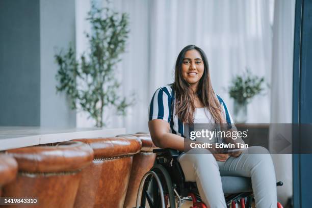 asiatische indische frau mit behinderungen, die im rollstuhl sitzt und lächelnd in die kamera schaut - man wheel chair stock-fotos und bilder