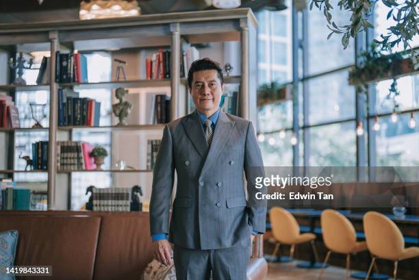 portrait asian chinese successful businessman looking at camera smiling standing at luxury hotel lobby - diretor geral imagens e fotografias de stock