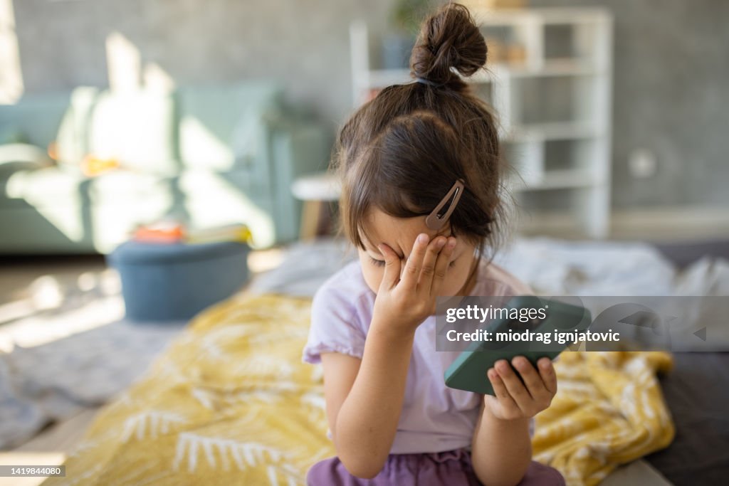 Tired Japanese girl using smartphone while relaxing on bed at home