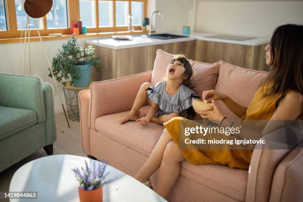 mother and daughter eating popcorn and enjoy day at home - catching food stock pictures, royalty-free photos & images