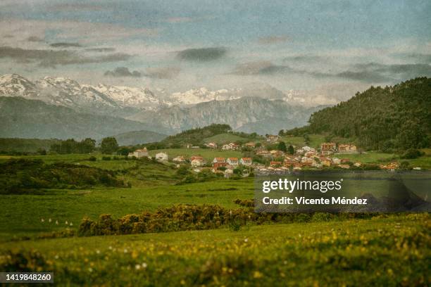 view of the town of prellezo with the picos de europa in the background - picos de europa fotografías e imágenes de stock