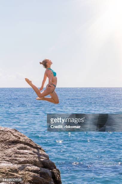 graceful jump off rock into turquoise sea of a teenage girl against the rays of the sun in the summer holidays - cliff diving stock pictures, royalty-free photos & images