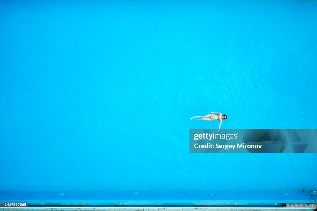 Drone view of woman swimming in pool