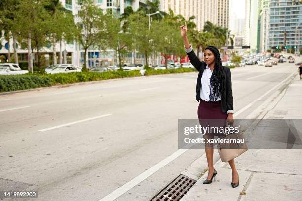 black miami businesswoman in mid 20s hailing a ride - miami streets stock pictures, royalty-free photos & images