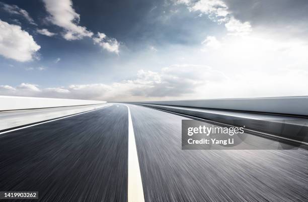 low and wide angle view of asphalt road with blurred motion in shine day - straßenmarkierung stock-fotos und bilder