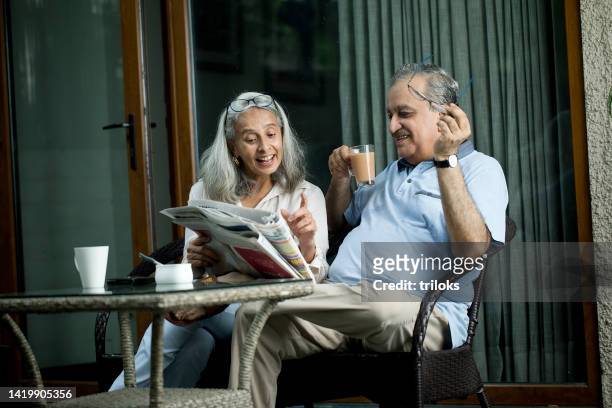 old couple reading newspaper and smiling - indian elderly couple stock pictures, royalty-free photos & images