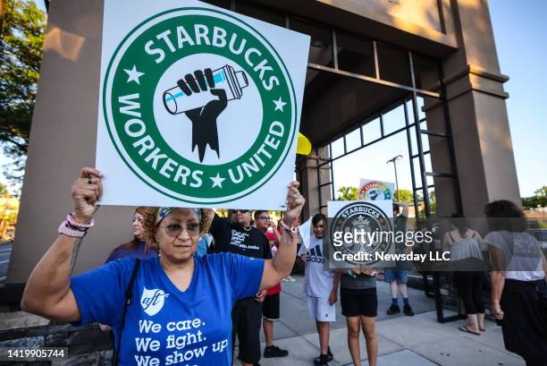 Woman holds up a sign as she joins other protestors in a rally against what they perceive to be union busting tactics, outside a Starbucks in Great...