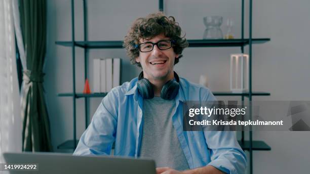 young adult man looking at camera happily after giving presentation via video conference. - translation 個照片及圖片檔