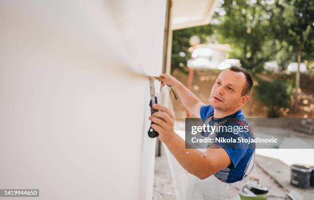 painter cuts styrofoam - plaster stockfoto's en -beelden