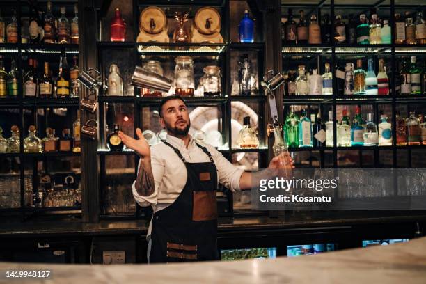 millennial bartender prepares refreshing alcoholic cocktails at the bar - bartender stock pictures, royalty-free photos & images