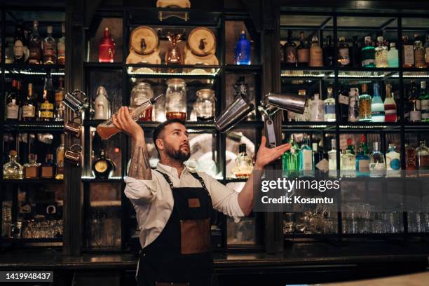 el apuesto camarero se para en el bar y prepara un refrescante cóctel alcohólico - barman fotografías e imágenes de stock