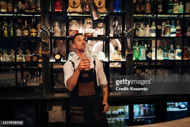 a professional bartender makes cocktails in a nightclub and enjoys it - steel bar stock pictures, royalty-free photos & images