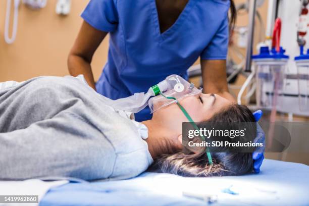 unrecognizable, caring emergency room nurse checks on female patient - hospital gurney stockfoto's en -beelden