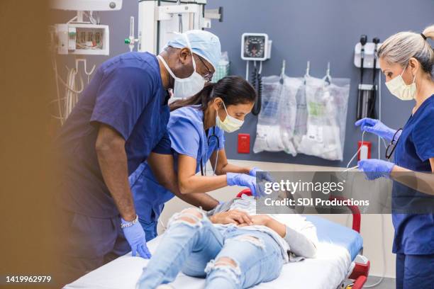 diverse emergency room team works on female patient - er stock pictures, royalty-free photos & images