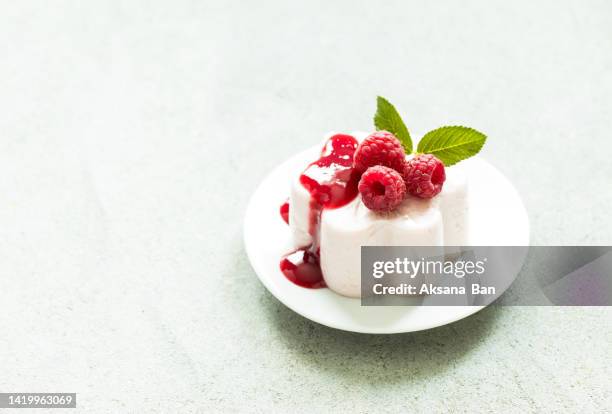 italian dessert, raspberry panna cotta with sauce on a plate. light gray background. copy space - dessert topping stock pictures, royalty-free photos & images