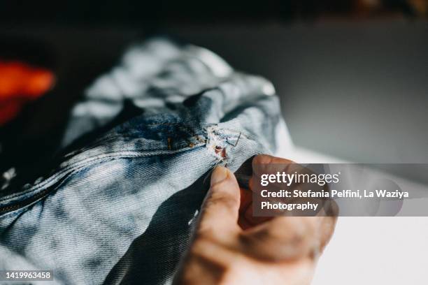 hands sewing a pair of jeans - textile patch stock-fotos und bilder