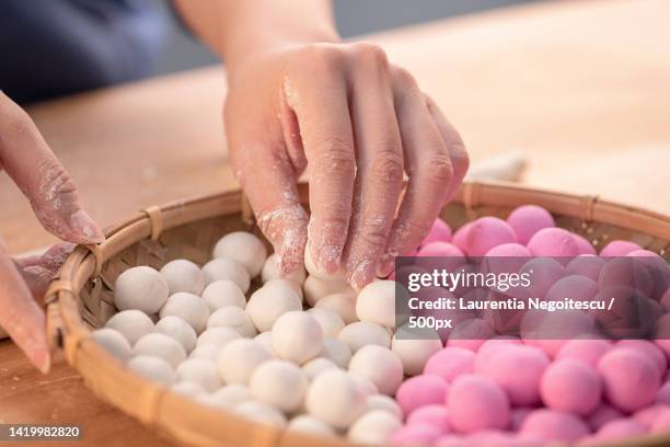 an asia woman is making tang yuan,yuan xiao,chinese traditional food rice dumplings in red and whi - winter solstice stock pictures, royalty-free photos & images