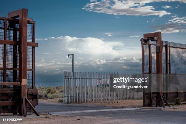 gate between united states/mexico border wall between sunland park, new mexico and puerto anapra chihuahua mexico near the santa teresa border crossing under a dramatic cloudscape near dusk - rio grande usa and mexico stock pictures, royalty-free photos & images