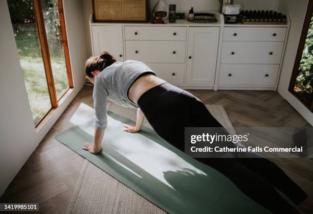 a woman holds a strenuous plank position on an exercise mat - self discipline stockfoto's en -beelden