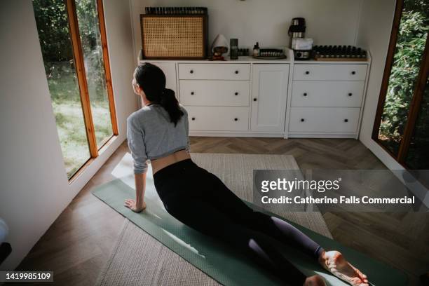 a woman stretches her lower back in the cobra pilates / yoga position - cobra stretch stock pictures, royalty-free photos & images