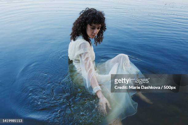 high angle view of young woman wearing white dress in water - beach model stock pictures, royalty-free photos & images