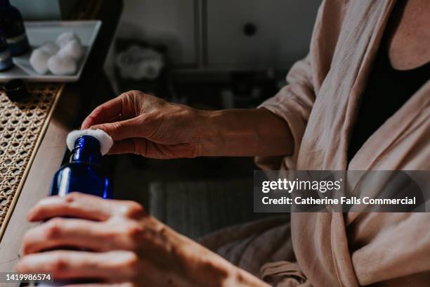 close-up of a woman pouring a liquid beauty product on to a cotton ball - woman applying cotton ball bildbanksfoton och bilder