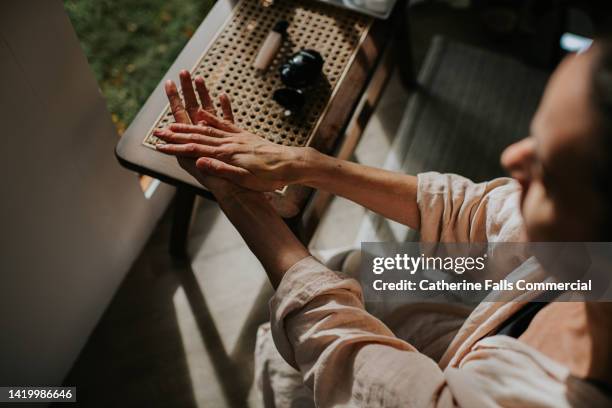 a woman moisturises her hands - belleza y salud fotografías e imágenes de stock