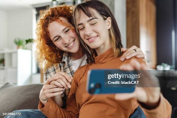 gay couple taking selfie at home - lesbian couple stock pictures, royalty-free photos & images