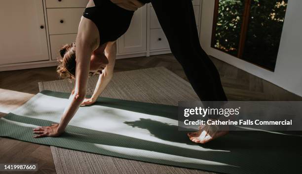 a woman performs the downwards dog yoga / pilates position on a exercise mat - me time stock pictures, royalty-free photos & images