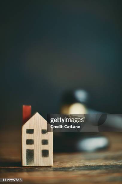 small wooden house with gavel in background. auction and legal theme - real estate law stock pictures, royalty-free photos & images