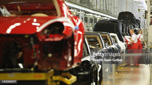 Workers assemble Porsche Cayenne and Panamera cars at an assembly line at the Porsche factory on March 28, 2012 in Leipzig, Germany. The Cayenne and...