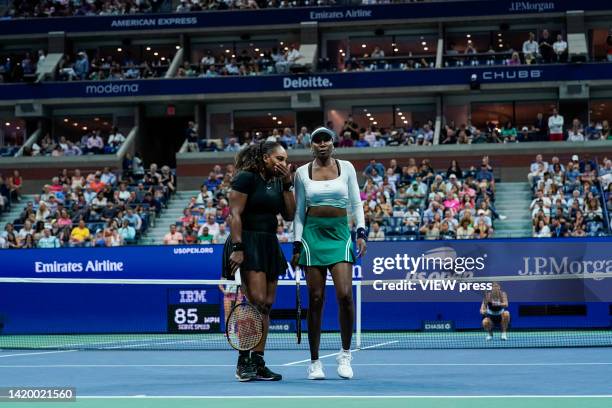 Serena Williams and Venus Williams of the United States talk on court after losing a point during their Women's Doubles First Round against Linda...