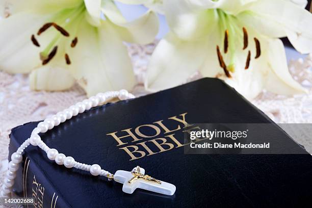 a rosary on a bible with easter lilies - easter lilies and cross stock-fotos und bilder