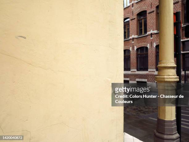 light yellow painted and weathered concrete wall with column, empty street and brick facade in brussels, belgium - street corner stock pictures, royalty-free photos & images